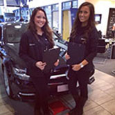 Two staff at a motor dealership collecting prospects data